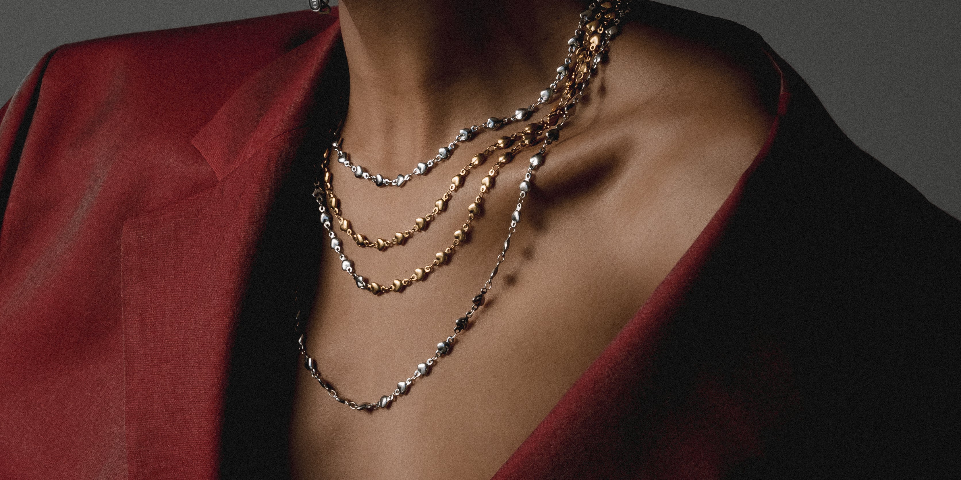 Model is wearing a black blazer with mixed metal silver and gold necklace