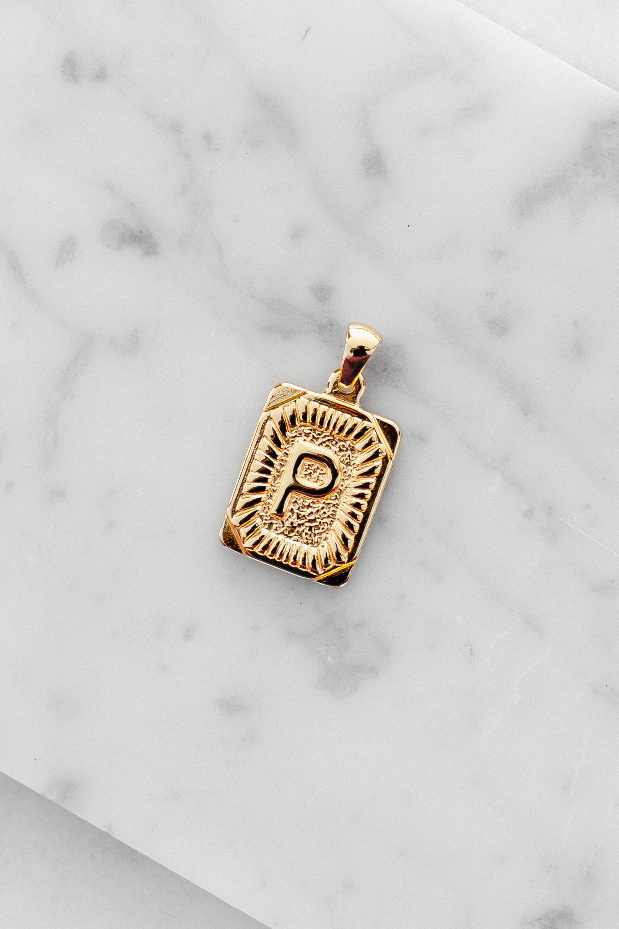 Gold Monogram Letter "P" Charm laying on a marble