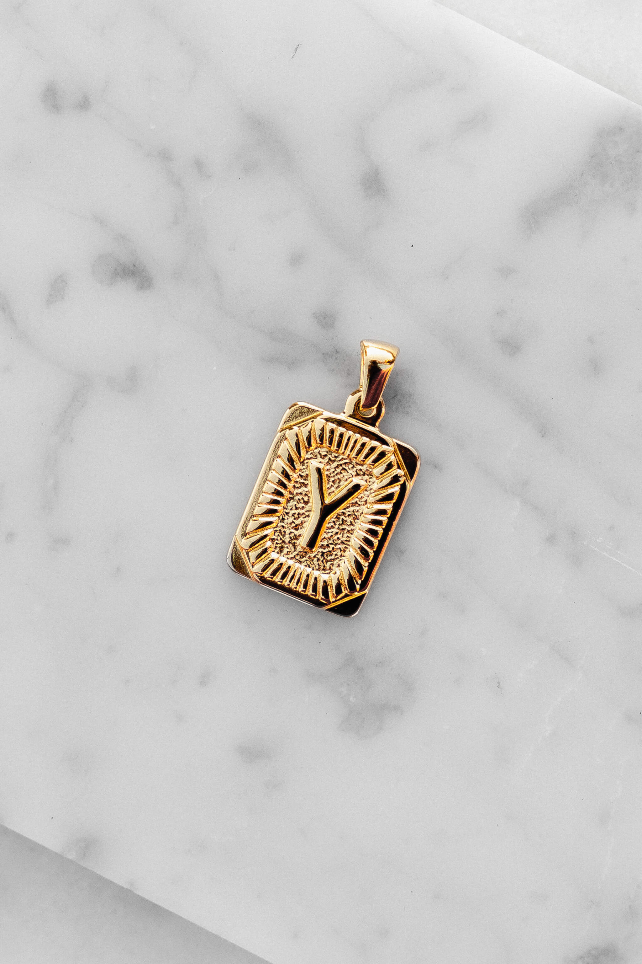 Gold Monogram Letter "Y" Charm laying on a marble