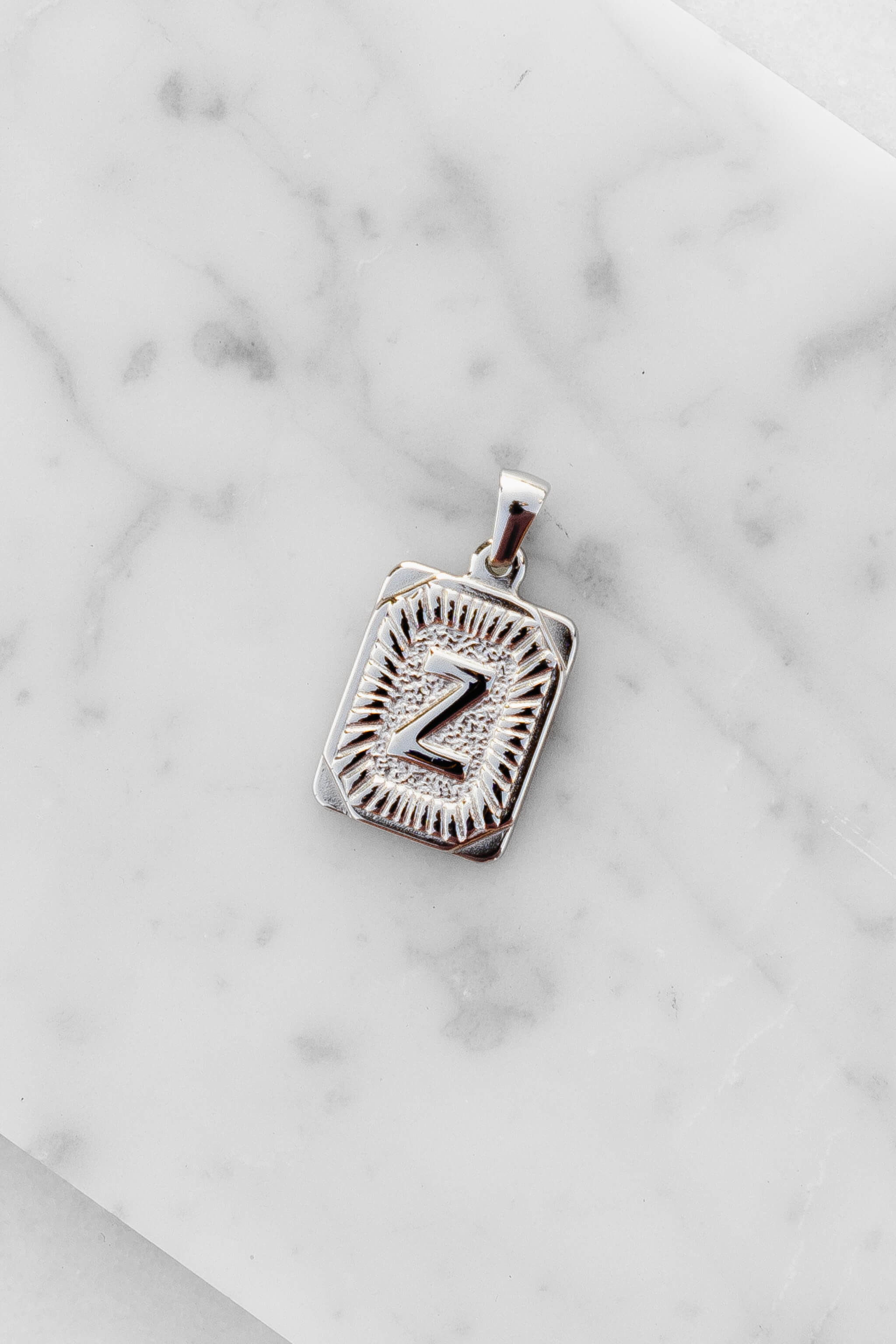 Silver Monogram Letter "Z" Charm laying on a marble