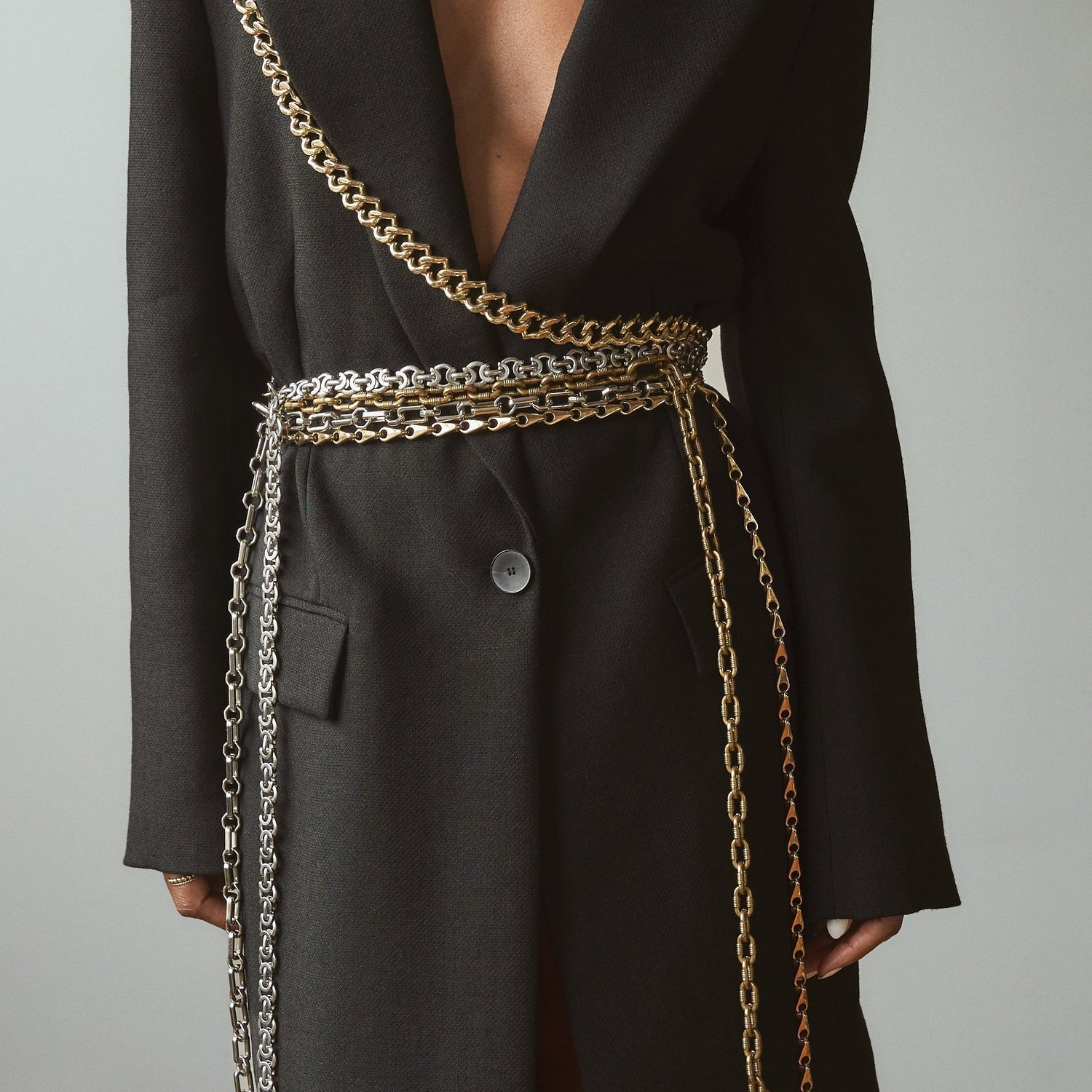 Model wearing Lapo Lounge Eris, Hyperion, Himalia and Zira chain belts layered over a black wool coat.