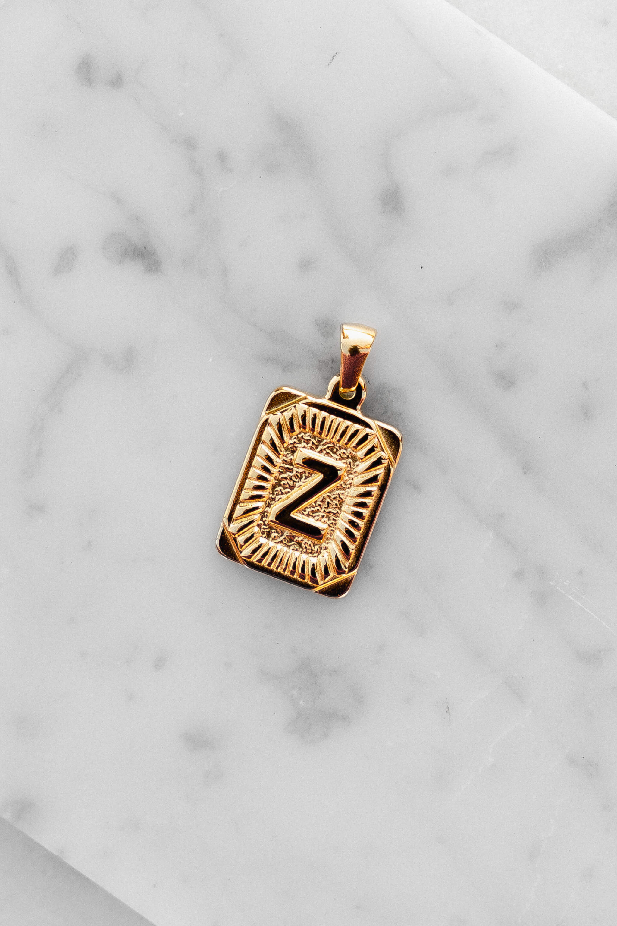 Gold Monogram Letter "Z" Charm laying on a marble