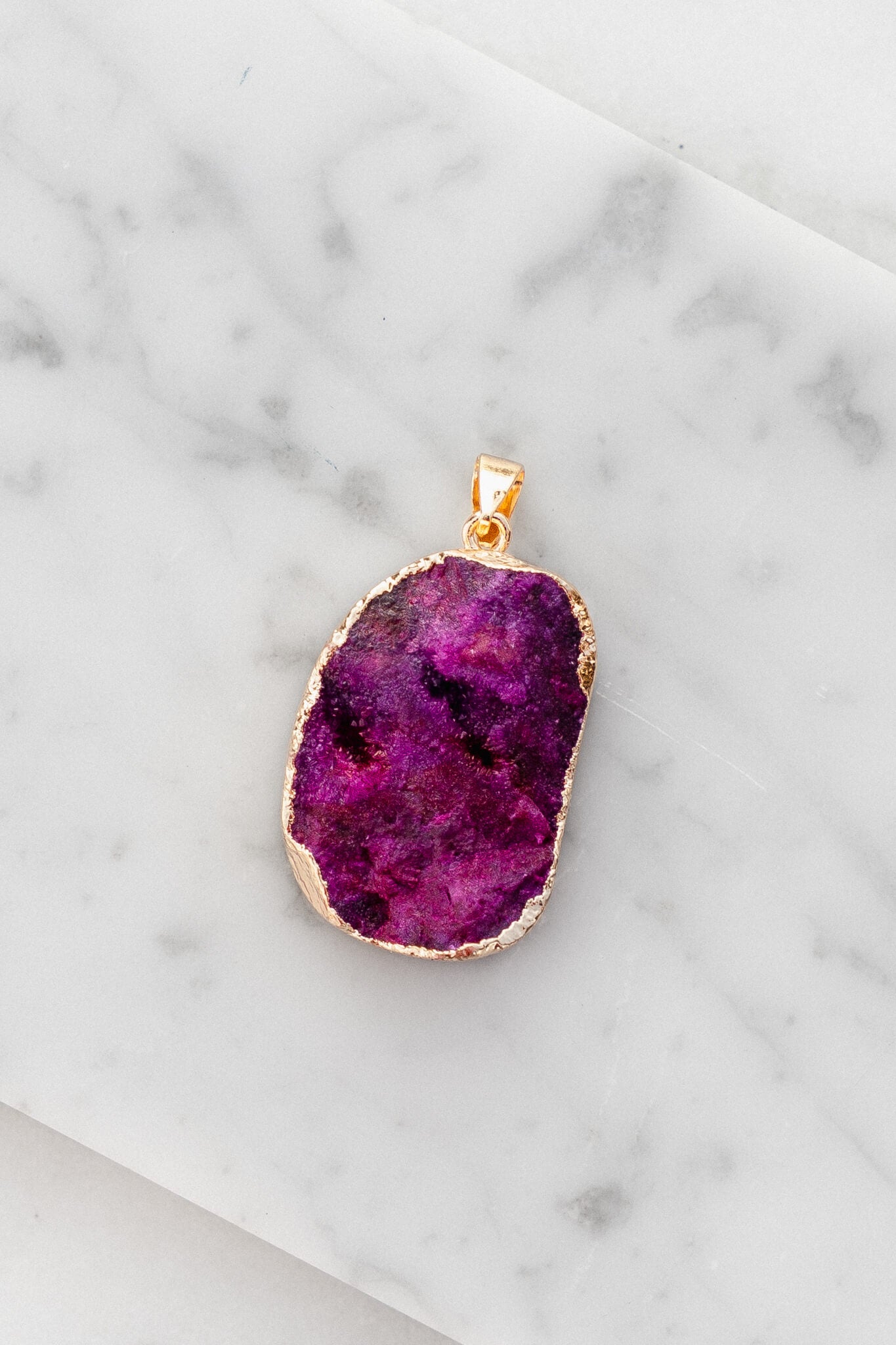 Purple Stone charm laying on a white marble